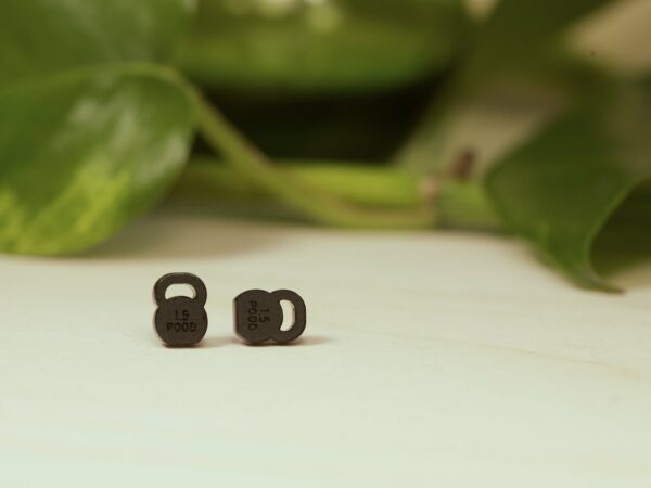 Small kettlebell stud earrings made from matte black acrylic.